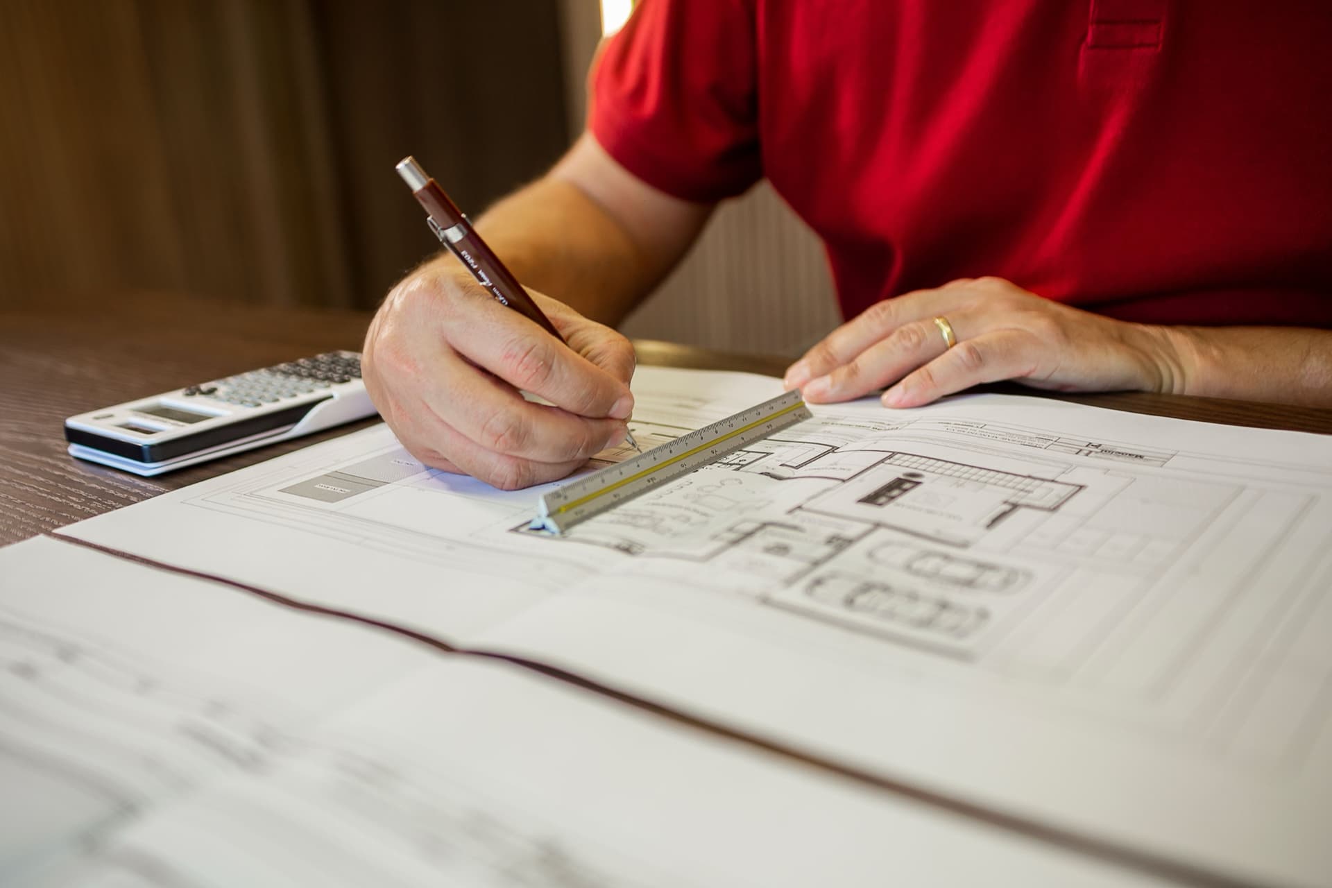 Estimator reviewing residential floor plans with a scale and calculator