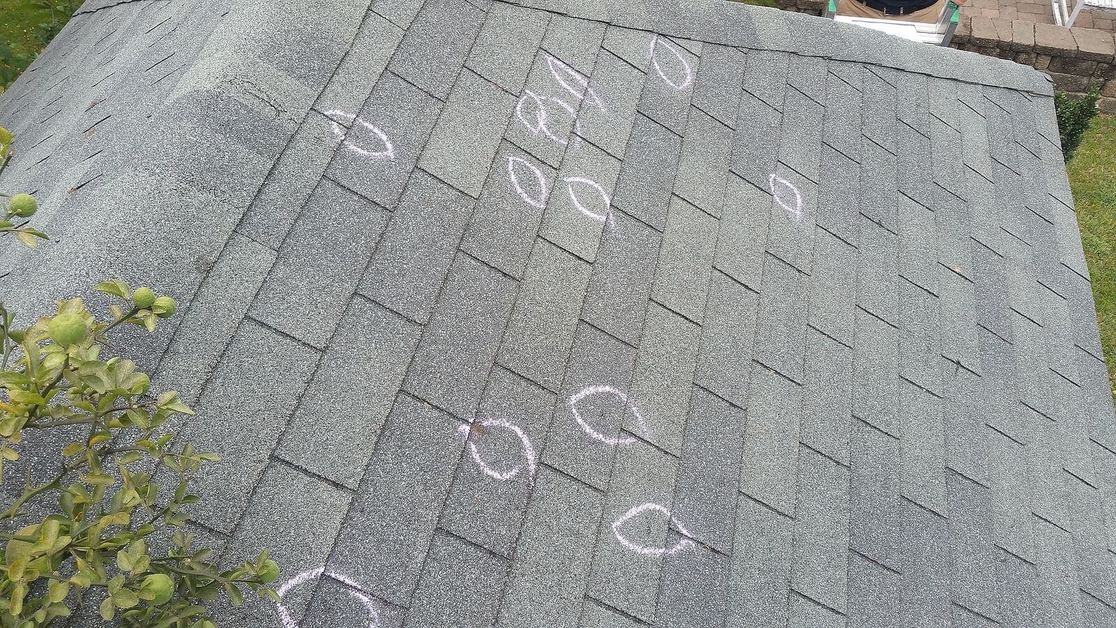 Chalk-marked observations on an asphalt-shingle roof during an inspection