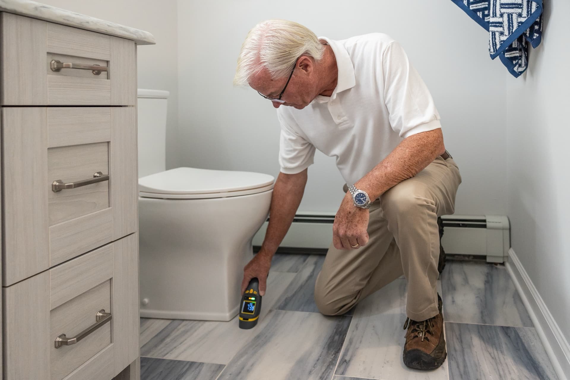 Inspector taking an instrument reading near the floor of a bathroom